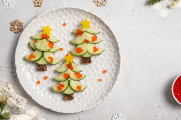Christmas tree sandwiches with cream cheese and cucumber on a light background, top view