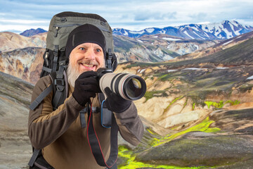 bearded man tourist photographer with a backpack photographs the beauty of nature in the mountains. nature hikes in the mountains