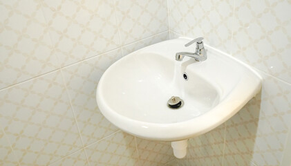 A hygienic white basin (washbowl) with stainless steel tap faucet in the clean bathroom for...
