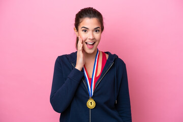 Young Brazilian sport woman with medals isolated on pink background with surprise and shocked...
