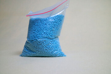 Blue NPK Fertilizer Granules in opp plastic, which functions as plant fertilizer. White isolated background