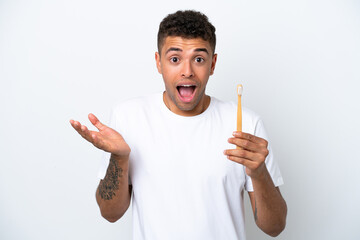 Young Brazilian man brushing teeth isolated on white background with shocked facial expression