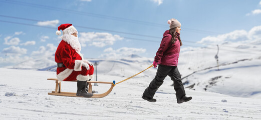 Girl pulling a sleigh with Santa claus on a mountain