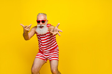 Photo of carefree good mood senior man wear red striped swimsuit having fun empty space isolated yellow color background
