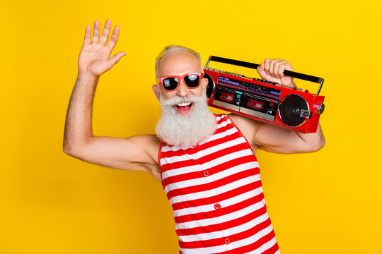Photo of man wear swimsuit carefree charismatic pensioner chill vibe raised hand up and listen boombox isolated on yellow color background