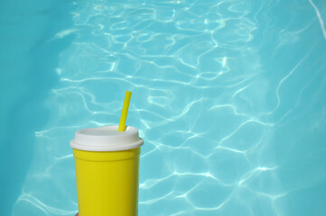 copo de água amarelo em fundo azul de piscina 