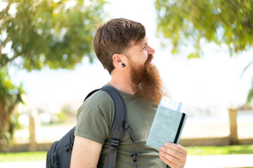 Fototapeta premium Redhead man with beard holding a passport at outdoors