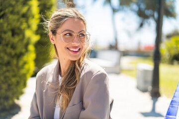 Pretty blonde Uruguayan woman with glasses at outdoors With happy expression - obrazy, fototapety, plakaty