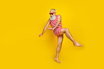 Full length photo of impressed funny senior man wear red striped swimsuit dancing discotheque empty space isolated yellow color background - obrazy, fototapety, plakaty