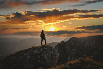 A man who hikers enjoys a break look at the top of the mountain at sunset adventure travel. - obrazy, fototapety, plakaty