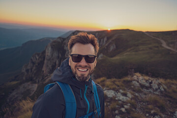 A smiling male traveler solo hiking the mountain adventure travel.