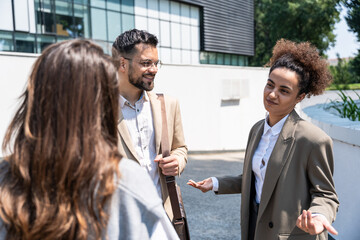 Group of successful young business people, leaders in marketing and motivation, stand in front of office building and consult before a meeting with employees. HR communication in companies concept