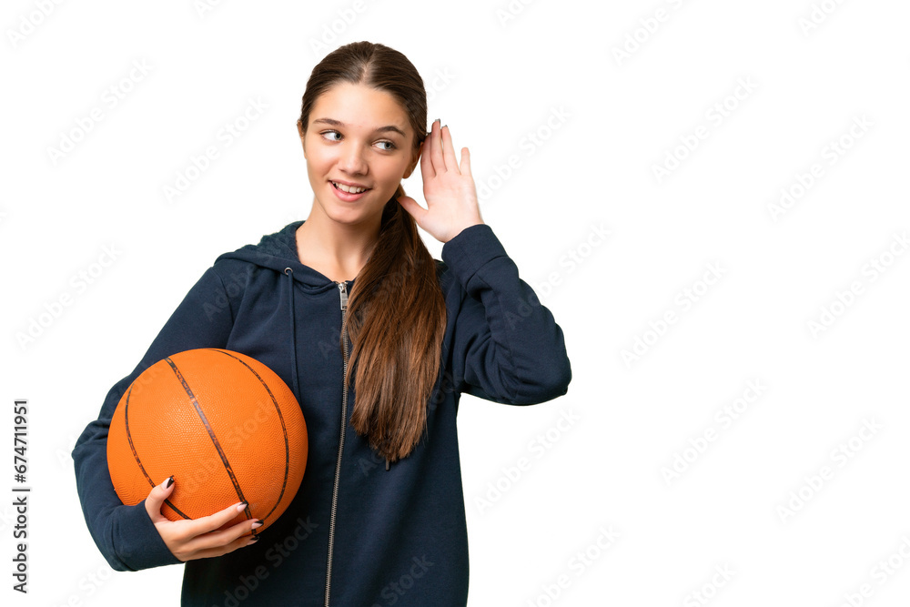 Sticker Teenager caucasian girl playing basketball over isolated background listening to something by putting hand on the ear