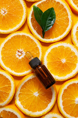 Orange organic  aromatic oil in a glass bottle with a pipette on a background of fresh orange slices