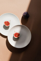 Still life with figs and plates. Photos in natural colors. Minimal food concept with dramatic light and shadow