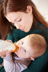 Face, woman and holding of baby with bottle for feeding in home for health, diet and nutrition with formula for hunger. Mother, watch and son for growth, development or milestone for future with care