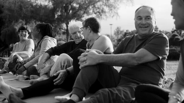 Multiracial senior people having fun together after yoga sport workout in nature city. Elderly international community. Black and white edit