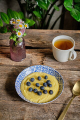 Sweet polenta porrige with blueberries. Top view, wooden background.