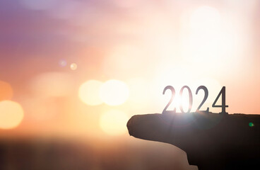 Happy New year 2024 with large silhouette letters on the mountain with sunset light
