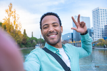 Young African American man taking a selfie looking at camera smiling - Point of view - Tourist...