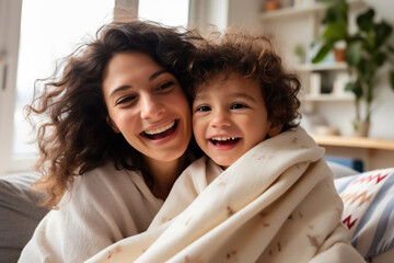 Happy young Latin mother and little son having fun on cozy couch in living room, overjoyed mum and preschool child tickling, cuddling, enjoying leisure time together - obrazy, fototapety, plakaty