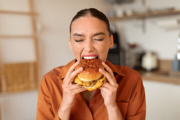 Woman eagerly biting into a savory burger at home