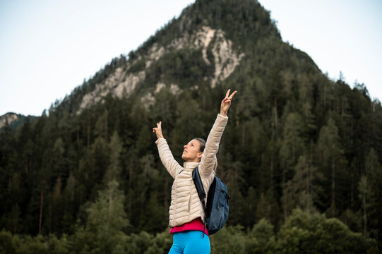 Woman with victoriously raised arms standing in mountaneous nature