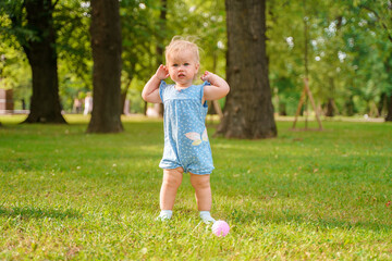 Cute baby child girl enjoys summer in a green park