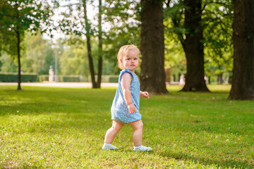 Cute baby child girl enjoys summer in a green park