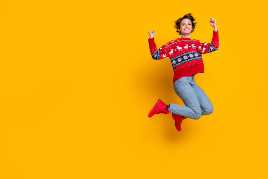 Full body photo of satisfied energetic woman wear sweater jumping clenching fists celebrate xmas isolated on yellow color background