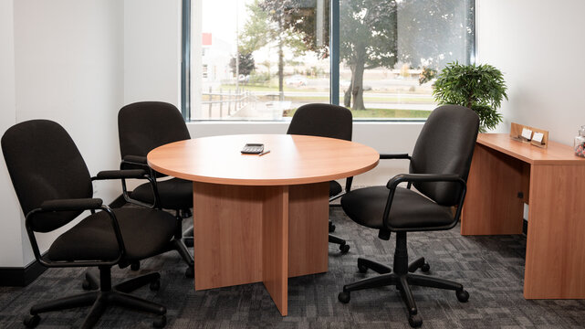 A comfortable and small meeting room in an office with 4 empty chairs.