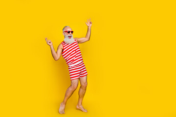 Full length photo of good mood excited senior man wear red striped swimsuit having fun empty space isolated yellow color background