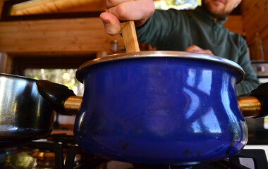 young person stirring a pot with wooden spoon