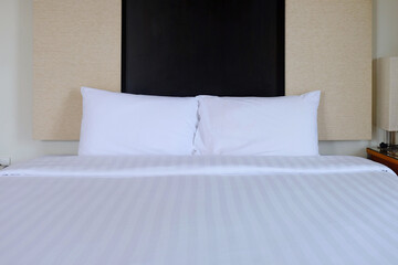 Front face of white clean arranged bed, king size, with pillows