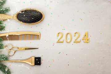Horizontal banner with golden hairdressing tools and numbers 2024. Winter holiday flatlay with hair salon accessories, Christmas tree branches, garland,confetti.