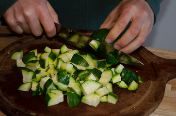 perona cutting zucchini on wooden board with knife