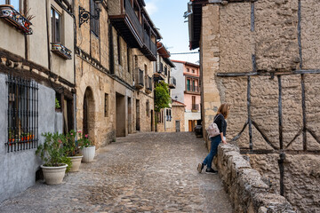 Tourist woman leaning out of the stone balcony overlooking the medieval city of Frias, Burgos.