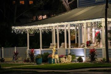 Brightly illuminated christmas decorations on front yard porch of florida family home. Outside decor for winter holidays