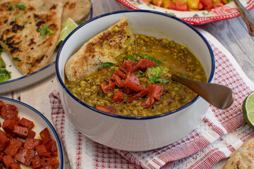 Vegan food spread consisting of lentils, naan, salad and fried seitan. White bowls,  stylish set up.