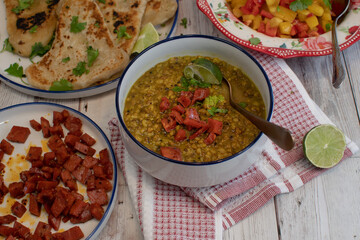Vegan food spread consisting of lentils, naan, salad and fried seitan. White bowls,  stylish set up.