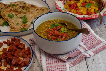 Vegan food spread consisting of lentils, naan, salad and fried seitan. White bowls,  stylish set up.