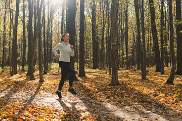Fototapeta premium Beautiful girl doing fitness in nature on a sunny autumn forest. Body positive, sports for women, harmony, healthy lifestyle, self-love and wellness.