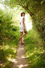 Portrait, smile and woman in hat in park in the countryside in summer, vacation and travel on holiday. Happy person in dress, woods and outdoor in nature at forest path, garden and field in Brazil