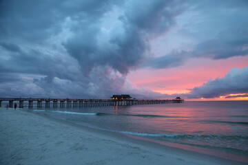 The Naples Beach pier at sunset and during a rough thunderstorm