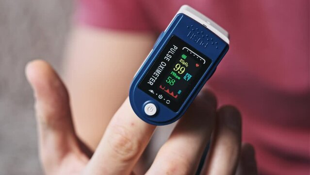 Pulse oximeter measures pulse and oxygen saturation on a male finger close-up. Modern device measure heart rate pulse and heartbeat health at home. Monitoring blood status. Health, medical technology