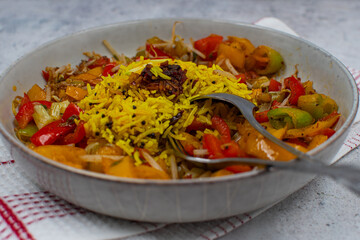 Vegan yellow rice pilaf with pepper curry  in  white bowl, fork and spoon