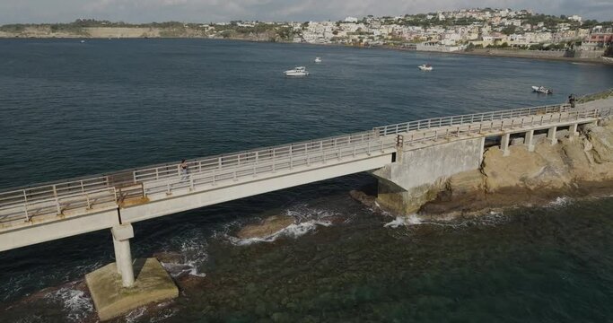Aerial view of a woman walking on Vivara bridge connecting Vivara Island Natural reserve and Procida Island, Flegree Islands archipelagos, Naples, Campania, Italy.