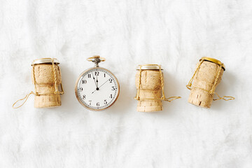 Vintage pocket watch show twelve clock, New Year time. Wine cork from sparkling wine on white fur...