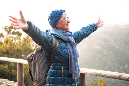 Happy senior woman with outstretched arms enjoying nature at the Garajonay national park in La Gomera. Elderly active woman hiking  in mountain admiring the panorama