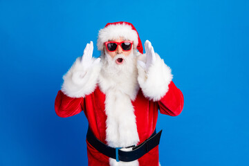 Photo portrait of mature pensioner man raise hands shocked dressed stylish santa claus costume coat isolated on blue color background